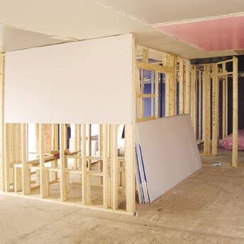 Two tapers in coveralls and dust masks applying joint compound to drywall walls